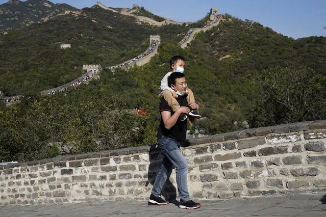 A man carries a child up a stretch of the Badaling Great Wall of China on the outskirts of Beijing on Tuesday, October 6, 2020. Chinese tourists took 425 million domestic trips in the first half of the eight-day National Day holiday, generating $45.9 billion in tourism revenue, according to China's ministry of culture and tourism. The holiday this year, which coincides with the Mid-Autumn Festival, will be a litmus test of whether China's tourism industry can bounce back after being battered by COVID-19. (Photo by Ng Han Guan/AP Photo)