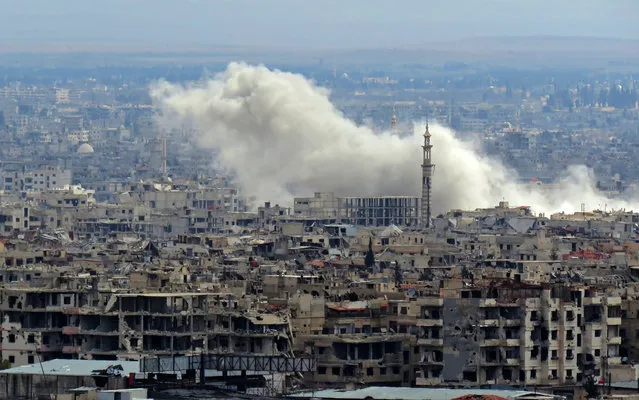 A general view taken from a government-held area in Damascus shows smoke rising from the rebel-held enclave of Eastern Ghouta on the outskirts of the Syrian capital following fresh air strikes and rocket fire on February 27, 2018. A fledgling “humanitarian pause” announced by Russia in Syria's rebel-held enclave of Eastern Ghouta was rattled by fresh air strikes and rocket fire, several sources said. (Photo by AFP Photo/Stringer)
