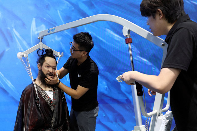 Staff members move a humanoid robot portraying emperor Qin Shi Huang from the Qin dynasty, which fell to the floor during a media tour in Beijing, China on August 6, 2025. (Photo by Florence Lo/Reuters)