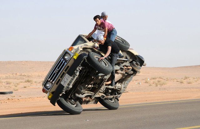 Saudi youths demonstrate a stunt known as “sidewall skiing” (driving on two wheels) in the northern city of Hail, in Saudi Arabia March 30, 2013. Performing stunts such as sidewall skiing and drifts is a popular hobby amongst Saudi youths. (Photo by Mohamed Al Hwaity/Reuters)