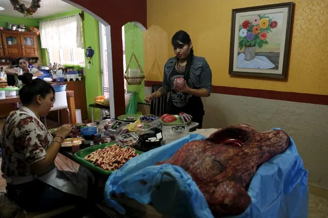 Joyce Matias (C), owner of a zombie gourmet candy manufacturer, works on a zombie baby head made of gummy candy in her house on the outskirts of Mexico City October 30, 2015. (Photo by Carlos Jasso/Reuters)