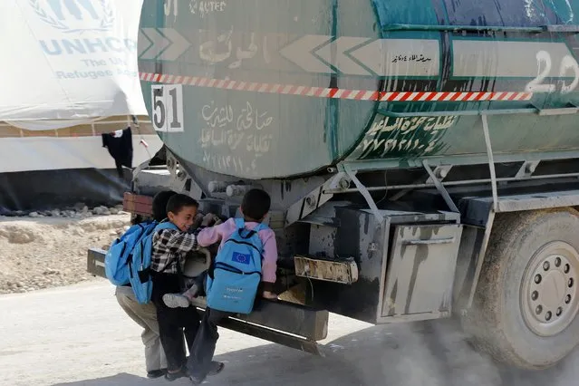 Syrian children hitch a ride from the back of a water tanker at the Al Zaatari refugee camp in the Jordanian city of Mafraq, near the border with Syria, December 7, 2014. (Photo by Muhammad Hamed/Reuters)