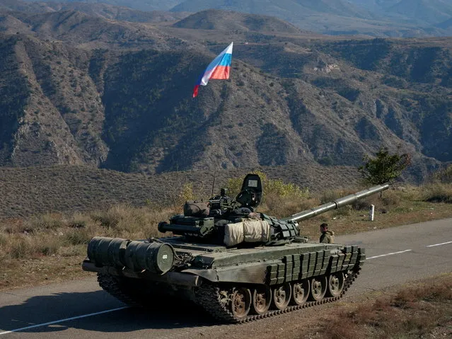 A service member of the Russian peacekeeping troops stands next to a tank near the border with Armenia, following the signing of a deal to end the military conflict between Azerbaijan and ethnic Armenian forces, in the region of Nagorno-Karabakh, November 10, 2020. (Photo by Francesco Brembati/Reuters)