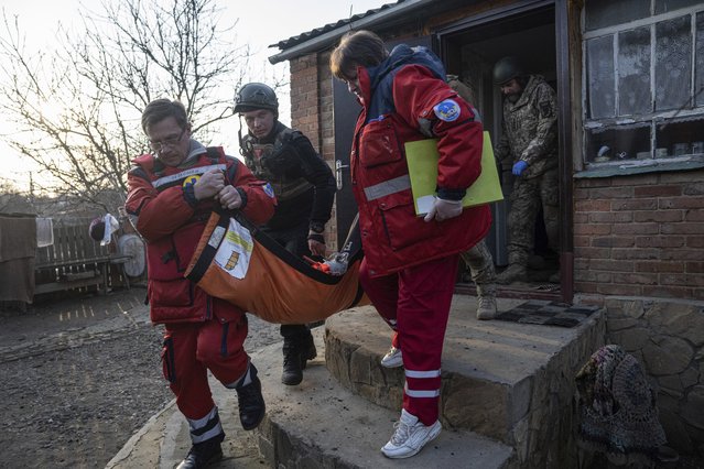Paramedics and Ukrainian police officers carry on a stretcher to the ambulance, a local resident Oleksandr Nikiforov, 49, which was injured by Russian shelling at the residential neighborhood near Kostiantynivka, Ukraine, Friday, March 10, 2023. (Photo by Evgeniy Maloletka/AP Photo)