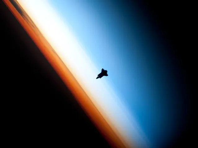 Though astronauts and cosmonauts often encounter striking scenes of Earth's limb, this unique image, part of a series over Earth's colorful horizon, has the added feature of a silhouette of the space shuttle Endeavour. The image was photographed by an Expedition 22 crew member prior to STS-130 rendezvous and docking operations with the International Space Station. Docking occurred at 11:06 p.m. (CST) on Feb. 9, 2010. The orbital outpost was at 46.9 south latitude and 80.5 west longitude, over the South Pacific Ocean off the coast of southern Chile, with an altitude of 183 nautical miles when the image was recorded. The orange layer is the troposphere, where all of the weather and clouds which we typically watch and experience are generated and contained. This orange layer gives way to the whitish Stratosphere and then into the Mesosphere. In some frames the black color is part of a window frame rather than the blackness of space. (Photo by NASA/Crew of Expedition 22)