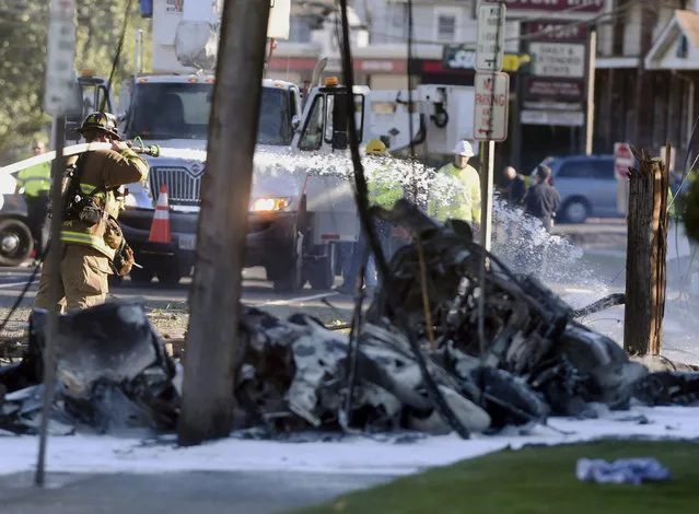 Firefighters use foam to extinguish the fire of a demolished aircraft after the plane crashed on Main Street in East Hartford Conn., Tuesday, October 11, 2016. Authorities said at least one person is dead and another is injured after a small airplane crashed near the Connecticut River. (Photo by Jim Michaud/Journal Inquirer via AP Photo)