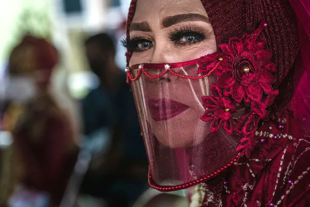 A bride, Sri Mujilestari, wear a transparant protective masks attend a mass wedding ceremony to commemorate the 75th Indonesia's National Independence Day at Cemara Sewu beach amid the Coronavirus pandemic on August 12, 2020 in Yogyakarta, Indonesia. Indonesia became an independent nation on 17th August 1945, having previously been under Dutch rule. Indonesia is struggling to contain hundreds of new daily cases of coronavirus amid easing of rules to allow economic activity to resume, and has reported more than 100,000 coronavirus cases and with at least more 5,900 recorded fatalities. (Photo by Ulet Ifansasti/Getty Images)