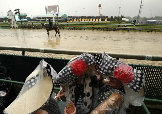 Fans huddle under plastic before the 144th running of the Kentucky Derby horse race at Churchill Downs Saturday, May 5, 2018, in Louisville, Ky. (Photo by Charlie Riedel/AP Photo)