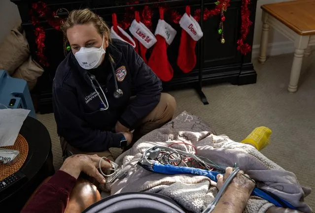 Community paramedic Karin Casciano speaks with a patient, 83, during a home wellness check on December 23, 2020 in White Plains, New York. The patient, an ex U.S. Marine, said the Christmas stockings were for his adult children, although he will not see them this Christmas because of the pandemic. Contracted by local hospitals, Empress EMS sends paramedics for follow-up visits to patients, some still COVID-19 positive, after their discharge from hospital stays. The visits are designed to help keep patients with chronic conditions healthy and out of the hospital, where they could either contract or spread COVID-19. (Photo by John Moore/Getty Images)