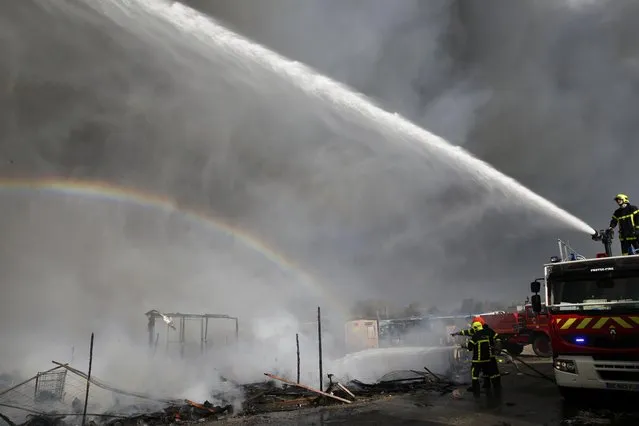 A rainbow is seen as firmen work to extinguish burning makeshift shelters in the “Jungle” on the third day of the evacuation and transfer of migrants to reception centers in France, as part of the dismantlement of the camp in Calais, France, October 26, 2016. (Photo by Pascal Rossignol/Reuters)