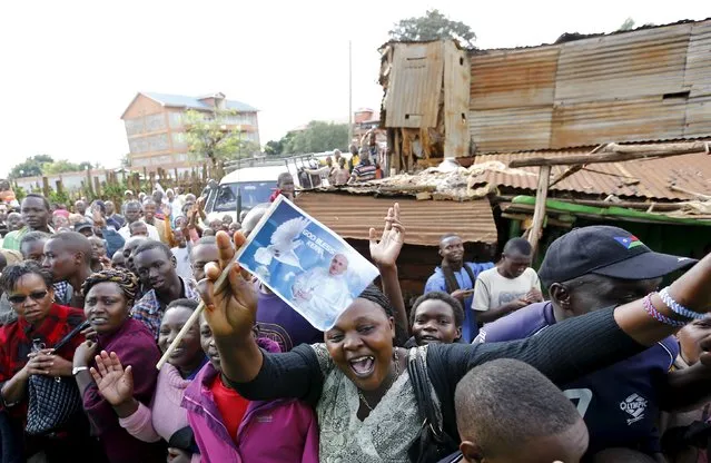 A woman holds a flag as Pope Francis' arrives at the Kangemi slums on the outskirt of Kenya's capital Nairobi November 27, 2015. (Photo by Stefano Rellandini/Reuters)