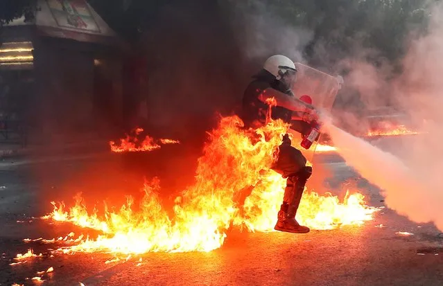 A riot police officer extinguishes a fire during a demonstration against government plans to regulate street protests, in front of the parliament building in Athens, Greece, July 9, 2020. (Photo by Alkis Konstantinidis/Reuters)