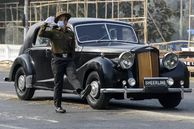 An Indian army soldier wearing a face mask to prevent the spread of the coronavirus marches alongside a vintage 1940 Austin A125 Sheerline car during rehearsals for Republic Day parade in Kolkata, India, Friday, January 22, 2021. (Photo by Bikas Das/AP Photo)