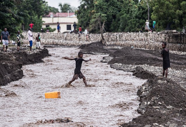 Children walk through a flooded street in the aftermath of Hurricane Melissa, in Petit-Goave, about 68 km (42 miles) southwest of Port-au-Prince, on October 31, 2025. In Haiti, the country's civil defense agency said on October 30 that the death toll from Hurricane Melissa had risen to 30, with 20 people injured and another 20 missing. (Photo by Clarens Siffroy/AFP Photo)