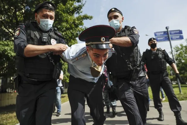 Police officers detains a protester, center, dressed as a Russian police officer before a court hearing of the New Greatness group who are charged with the organization of an extremist association in Moscow, Russia, Thursday, August 6, 2020. Arrests of the two youngest members of the New Greatness group – 17-year-old Anna Pavlikova and 19-year-old Maria Dubovik – prompted a mass protest in August 2018, after which the two teenagers were released under house arrest. (Photo by Pavel Golovkin/AP Photo)