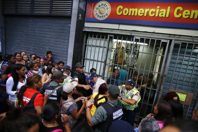 People line up to buy toilet paper and baby diapers as national guards control the access at a supermarket in downtown Caracas January 19, 2015. There's a booming new profession in Venezuela: standing in line. The job usually involves starting before dawn, enduring long hours under the Caribbean sun, dodging or bribing police, and then selling a coveted spot at the front of huge shopping lines. (Photo by Jorge Silva/Reuters)