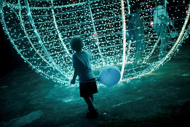 A child holds a balloon during a Christmas lighting-up ceremony in Rio de Janeiro, Brazil, on December 6, 2025. (Photo by Tita Barros/Reuters)