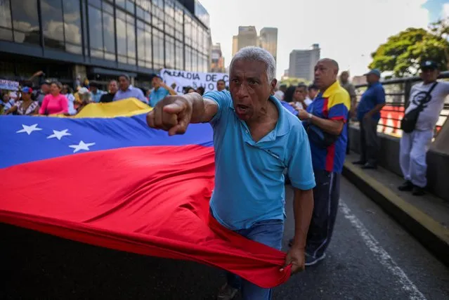 A man holding a Venezuelan flag gestures as union workers, members of political opposition parties, and others participate in a protest against the government of Venezuela's President Nicolas Maduro during May Day, in Caracas, Venezuela on May 1, 2023. (Photo by Gaby Oraa/Reuters)