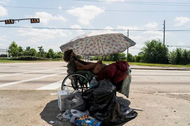 Tony, a homeless man, sits under his umbrella to avoid sun light during hot weather in Houston, Texas, U.S. June 28, 2023. (Photo by Go Nakamura/Reuters)