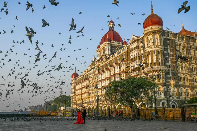 A couple poses for photographs in front of the Taj Mahal hotel in Mumbai on March 4, 2021. (Photo by Punit Paranjpe/AFP Photo)