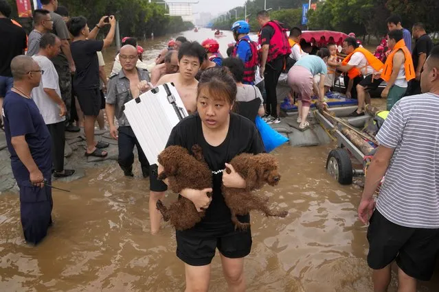 A woman carries her pet dogs as residents are evacuated on rubber boats through floodwaters in Zhuozhou in northern China's Hebei province, south of Beijing, Wednesday, August 2, 2023. China's capital has recorded its heaviest rainfall in at least 140 years over the past few days. Among the hardest hit areas is Zhuozhou, a small city that borders Beijing's southwest. (Photo by Andy Wong/AP Photo)