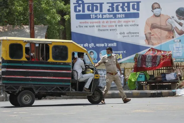 A police man stops an auto rickshaw at a check point during a weekend lockdown to curb the spread of coronavirus in Prayagraj, India, Sunday, April 18, 2021. (Photo by Rajesh Kumar Singh/AP Photo)