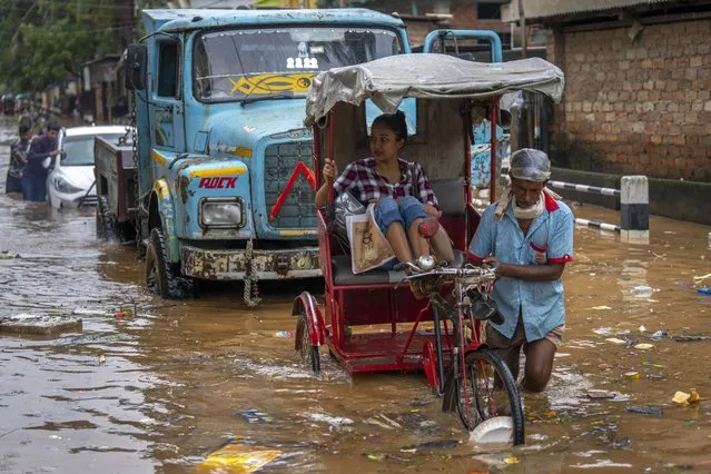 A rickshaw driver ferries a passenger past a flooded street after continuous rainfall in Gauhati, India, Wednesday, June 15, 2022.  With rising global temperatures due to climate change, experts say the monsoon is becoming more variable, meaning that much of the rain that would typically fall in a season is arriving in a shorter period of time. (Photo by Anupam Nath/AP Photo)