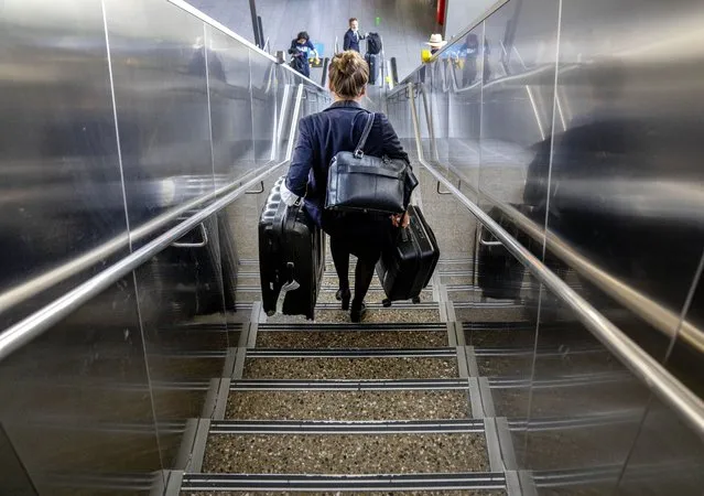 A woman carries her luggage down the stairs at the international airport in Frankfurt, Germany, Tuesday, June 21, 2022. After two years of pandemic restrictions, travel demand is back with a vengeance but airlines and airports that slashed jobs during the depths of the COVID-19 crisis are struggling to keep up. With the busy summer tourism season underway in Europe, passengers are encountering chaotic scenes at airports, including lengthy delays, canceled flights and headaches over lost luggage. (Photo by Michael Probst/AP Photo)