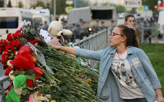 A woman lays flowers at a makeshift memorial for victims of a deadly shooting at School Number 175 in Kazan, Russia on May 11, 2021. At least nine people, most of them children, were killed on May 11, 2021 when a lone teenage gunman opened fire at a school in the central Russian city of Kazan, officials said. (Photo by Artem Dergunov/Reuters)