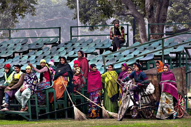 Indian sweepers and laborers take time out to watch different branches of Indian military practice a march past as they rehearse to participate in the Republic Day parade in New Delhi, India, Wednesday, January 20, 2016. India celebrates Republic Day on Jan. 26 every year, highlighted by a march past by different branches of the military as well as a display of arms and missiles. (Photo by Bernat Armangue/AP Photo)