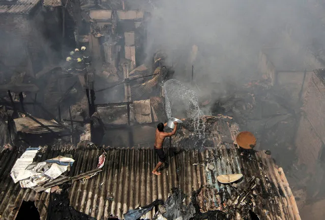 A man pours water to douse a fire that broke out in a slum in Mumbai, India, October 30, 2018. (Photo by Prashant Waydande/Reuters)