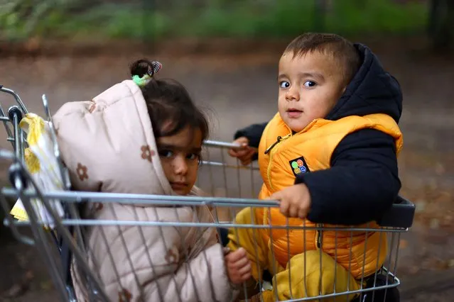 Murat Ayaz, 2, and his sister Halime, 3, from the Turkish city of Diyarbakır are pictured in a shopping trolley as they are on their way with their parents (not pictured) to a first accommodation compound for migrants at the arrival center for asylum seekers at Berlin's Reinickendorf district, Germany on October 6, 2023. (Photo by Fabrizio Bensch/Reuters)