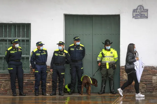 National Police wearing the force's new, blue uniforms stand by an officer wearing the old one, right with dog, as they stand guard on the sidelines of the ceremony presenting the new uniforms at Plaza de Bolivar in Bogota, Colombia, Monday, July 19, 2021. The uniforms changed from green to blue, and an arm patch features a QR code that allows anyone who scans it to see the officer's name, rank and badge number. (Photo by Ivan Valencia/AP Photo)