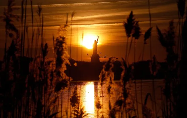 The sun rises behind the Statue of Liberty in New York City on November 4, 2023, as seen from Jersey City, New Jersey. (Photo by Gary Hershorn/Getty Images)