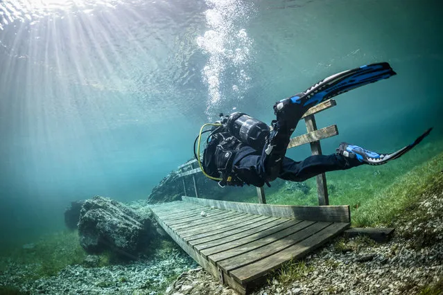 A diver crossing a bridge in the flood water. Green Lake in Tragoess, Austria. (Photo by Solnet/The Grosby Group)