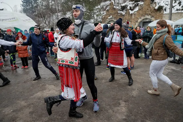 Moldavians dressed in traditional costumes dance with participants before the “Milestii Mici Wine Run 2019” race, at a distance of 10 km in the world's largest wine cellars in Milestii Mici, Moldova January 20, 2019. (Photo by Gleb Garanich/Reuters)