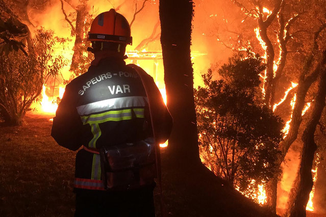 In this photo provided by the fire brigade of the Var region, a fireman battles with a fire near Toulon early Tuesday, August 17, 2021. Hundreds of firefighters on Tuesday battled a fire racing through forests near the French Riviera that forced the evacuation of thousands of people from homes and vacation spots. (Photo by SDIS 83 via AP Photo)