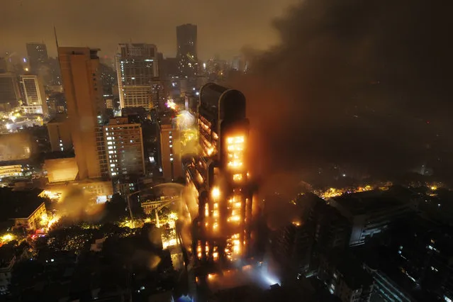 Firemen try to put down the fire on a 25-floor uninhabited building in a shopping district in Guangzhou on December 16, 2013 in Guangdong province, China.   The fire started about 7pm Sunday and got under control by Monday morning. The building was built more than two decades ago and was used as a warehouse later as the constructor didn't finish it. (Photo by Feature China/Barcroft Media)