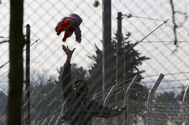 A migrant plays with his baby as they wait to enter Macedonia from Greece near Gevgelija, Macedonia, February 19, 2016. (Photo by Ognen Teofilvovski/Reuters)