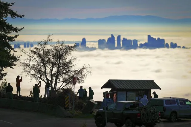 People are silhouetted at the Cypress Mountain Lookout in West Vancouver, British Columbia, while viewing fog blanketing the Metro Vancouver area, on Sunday, November 26, 2023. (Photo by Darryl Dyck/The Canadian Press via AP Photo)