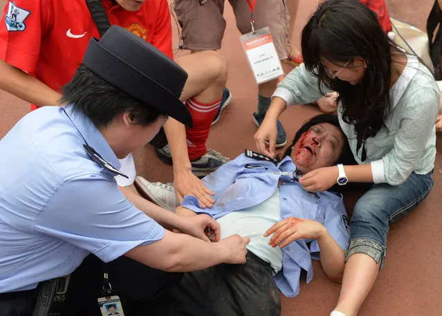 A policewoman is treated for injuries after being crushed in a stampede to see football superstar David Beckham at Tonji University in Shanghai on June 20, 2013. Five people were injured when hundreds of students poured through a gate to see the recently retired former England captain who is here on a seven day visit to China. (Photo by Peter Parks/Reuters)