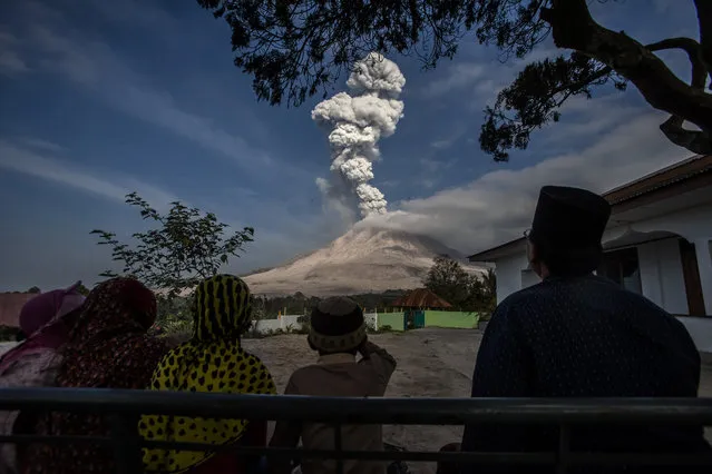 Residents watch volcanic smoking and ashes rising from Mount Sinabung during an eruption in Karo, North Sumatra, Indonesia, February 24, 2016. Authorities have repeatedly called on local residents to remain patient in dealing with the impact of Sinabung's eruptions, which some experts have predicted will continue for five more years. (Photo by Xinhua/Barcroft Media)