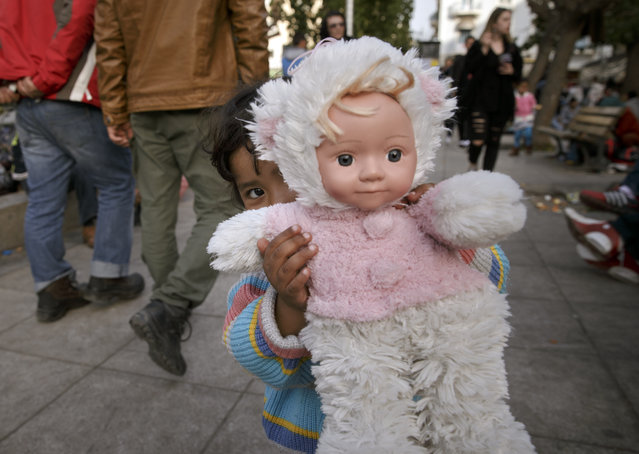 A child of a migrant family holds a doll in Athens, Monday, February 29, 2016, at the Victoria Square where most newly-landed migrants head after reaching the Greek capital from the Aegean Sea islands. (Photo by Vadim Ghirda/AP Photo)