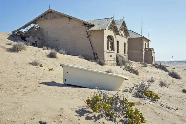 These sand-swept images show the ghostly remains of what was once a mineral-rich mining community. In its heyday, the town of Kolmanskop, Namibia, was home to about 700 families. Now all that remains are empty homes filled with sand, while cast-off items such as bathtubs are scattered about the surrounding area. Over time, the sand of the stunning dunes that encircle the town of Kolmanskop has been blown towards the abandoned residences, coating everything from streets to the interiors of houses and workshops. Here: Kolmankop, an abandoned mining town in Namibia. (Photo by David Ogden/Caters News)