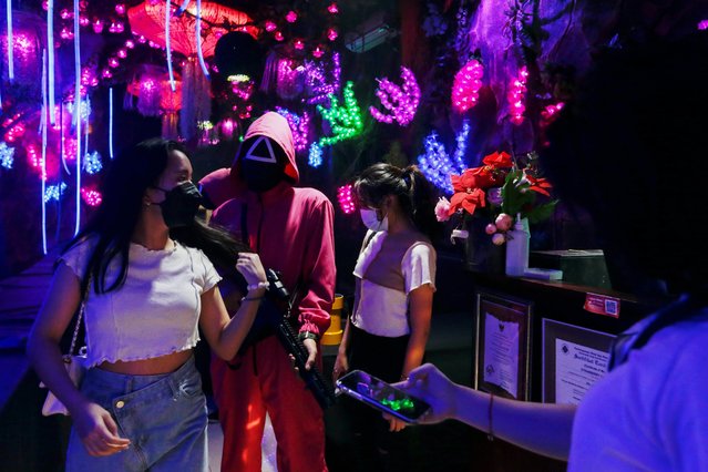 Customers get ready to take a photo with a staff member wearing “Squid Game” costume at Strawberry Cafe in Jakarta, Indonesia, October 15, 2021. (Photo by Ajeng Dinar Ulfiana/Reuters)
