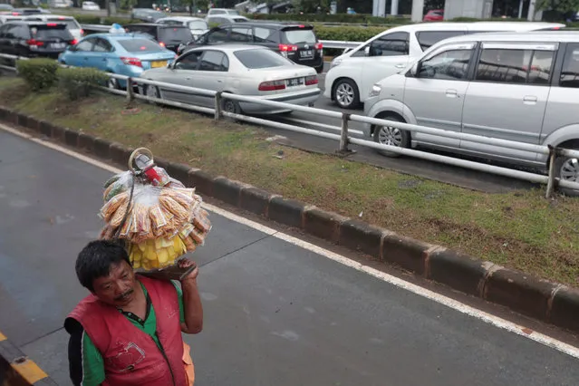 A street vendor carries food next to a traffic jam along a road in Jakarta, Indonesia February 1, 2017. (Photo by Reuters/Beawiharta)