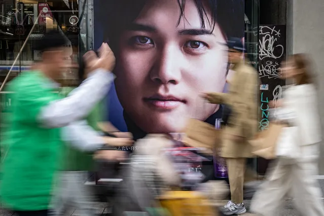 People walk past an advertisement with a picture of Major League Baseball (MLB) baseball star Shohei Ohtani, who plays for the Los Angeles Dodgers, in Tokyo on March 17, 2024. (Photo by Yuichi Yamazaki/AFP Photo)