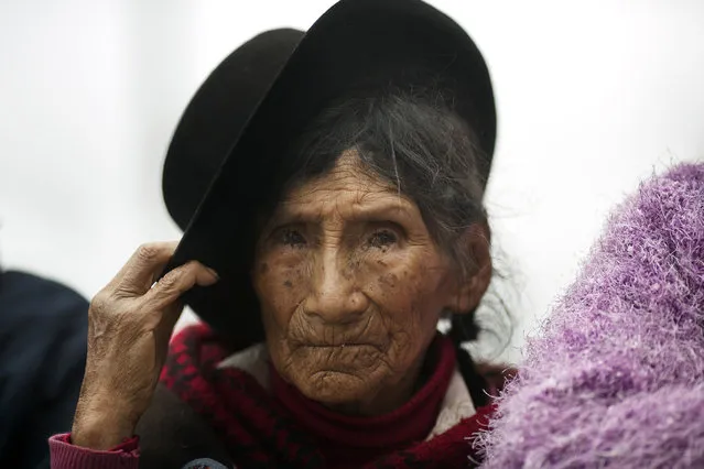 In this March, 29, 2016 photo, a woman waits for the return of the remains of over 30 people who were killed more than two decades ago in Ccano, a village in the Huanta area of Ayachcuo department, Peru. The villagers were killed by Shining Path guerrillas in the village's church in 1991, at the start of Alberto Fujimori’s presidency. (Photo by Rodrigo Abd/AP Photo)