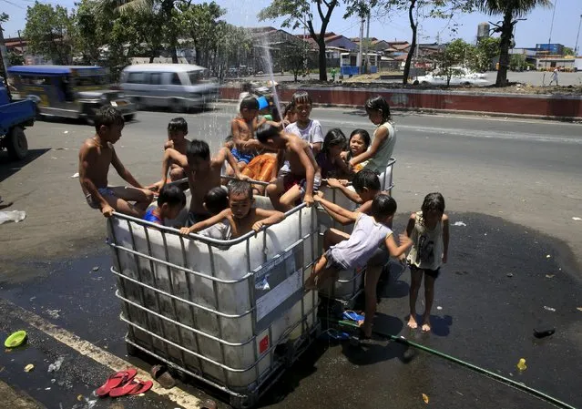 Children take a dip in a container outfitted as a swimming pool, to cool off from the intense heat, in Manila April 11, 2016. (Photo by Romeo Ranoco/Reuters)