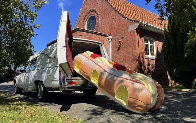 This photo provided by Ross Hall, shows a cream doughnut shaped coffin for the funeral of Phil McLean outside a church in Tauranga, New Zealand on February 17, 2021. Auckland company Dying Art makes unique custom caskets which reflect the people who will eventually lay inside them, whether it's a love for fire engines, a cream doughnut or Lego. (Photo by Ross Hall via AP Photo)